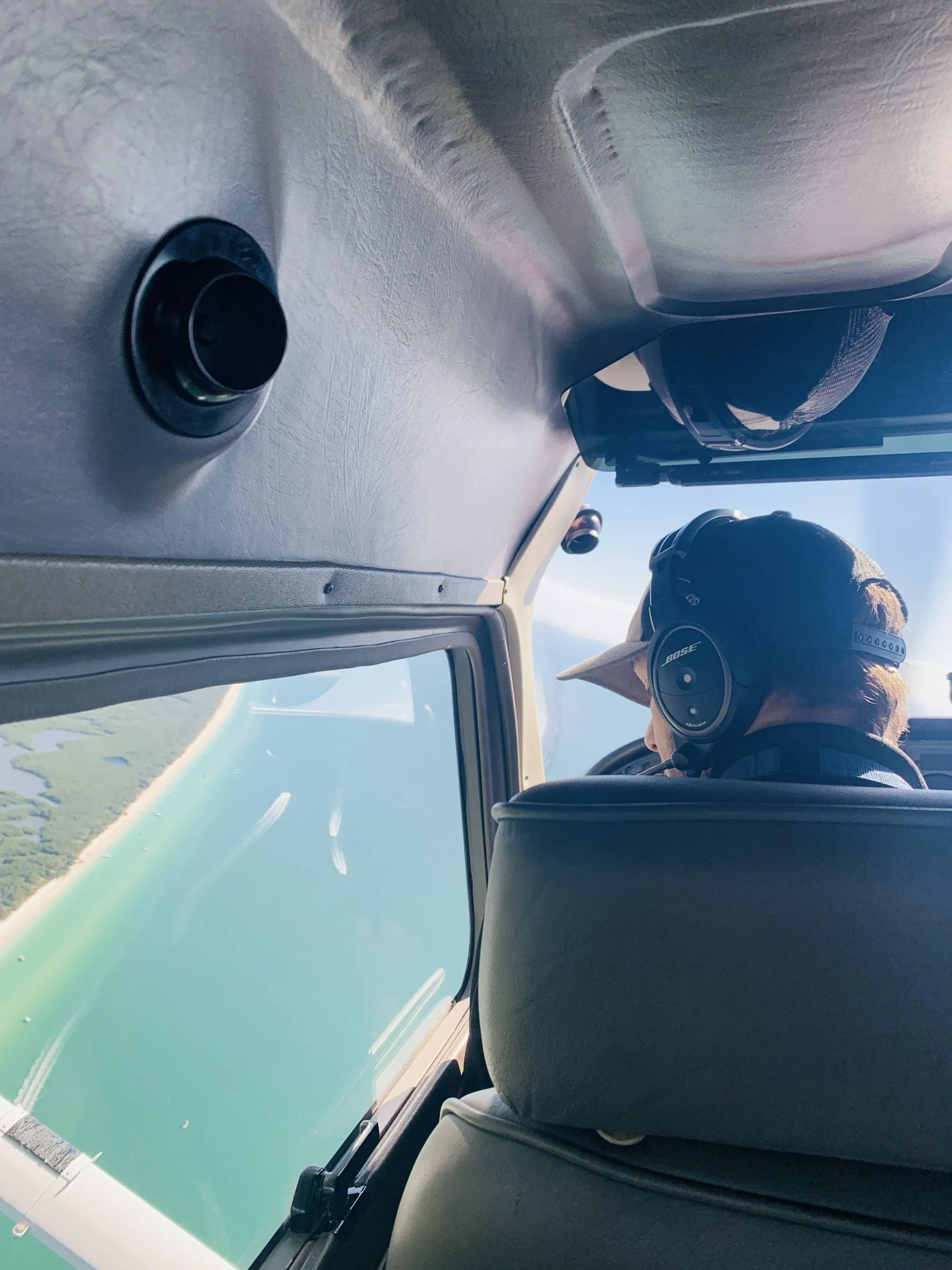Pilot in a headset looking out over a turquoise Gulf coastline